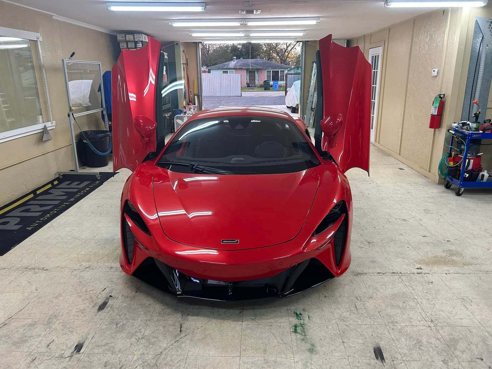 Red sports car with open doors in a garage.