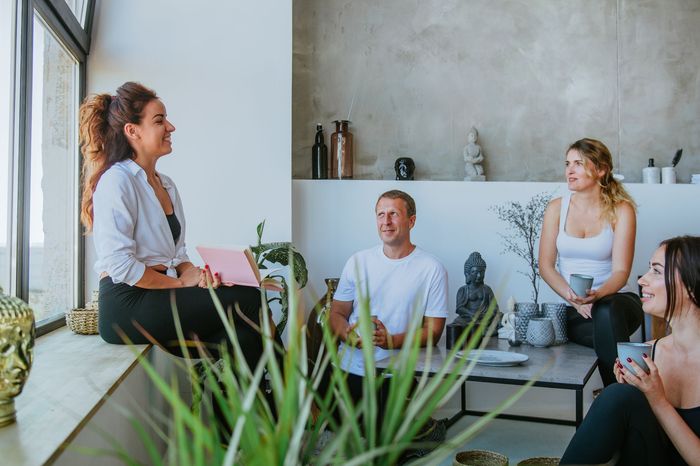 A group of people are sitting around a table in a living room.