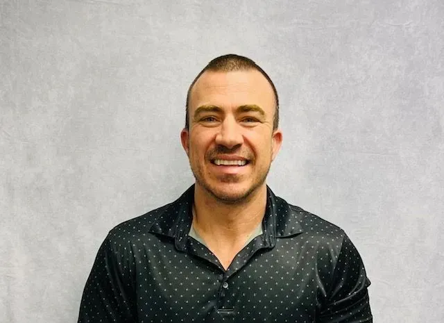 A man in a black shirt is smiling for the camera.