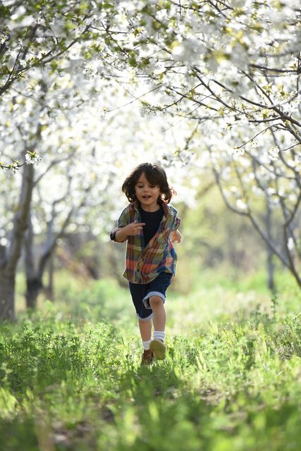 A little boy is running through a field of flowers.