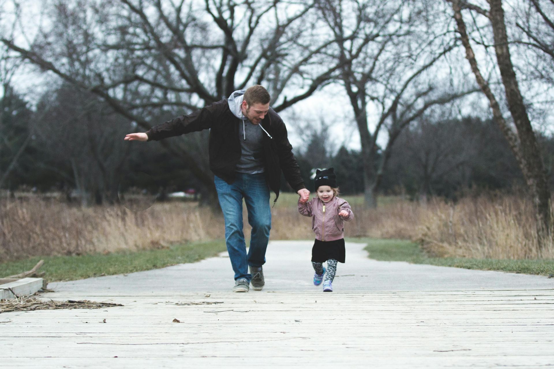 A man and a little girl are walking down a path holding hands.