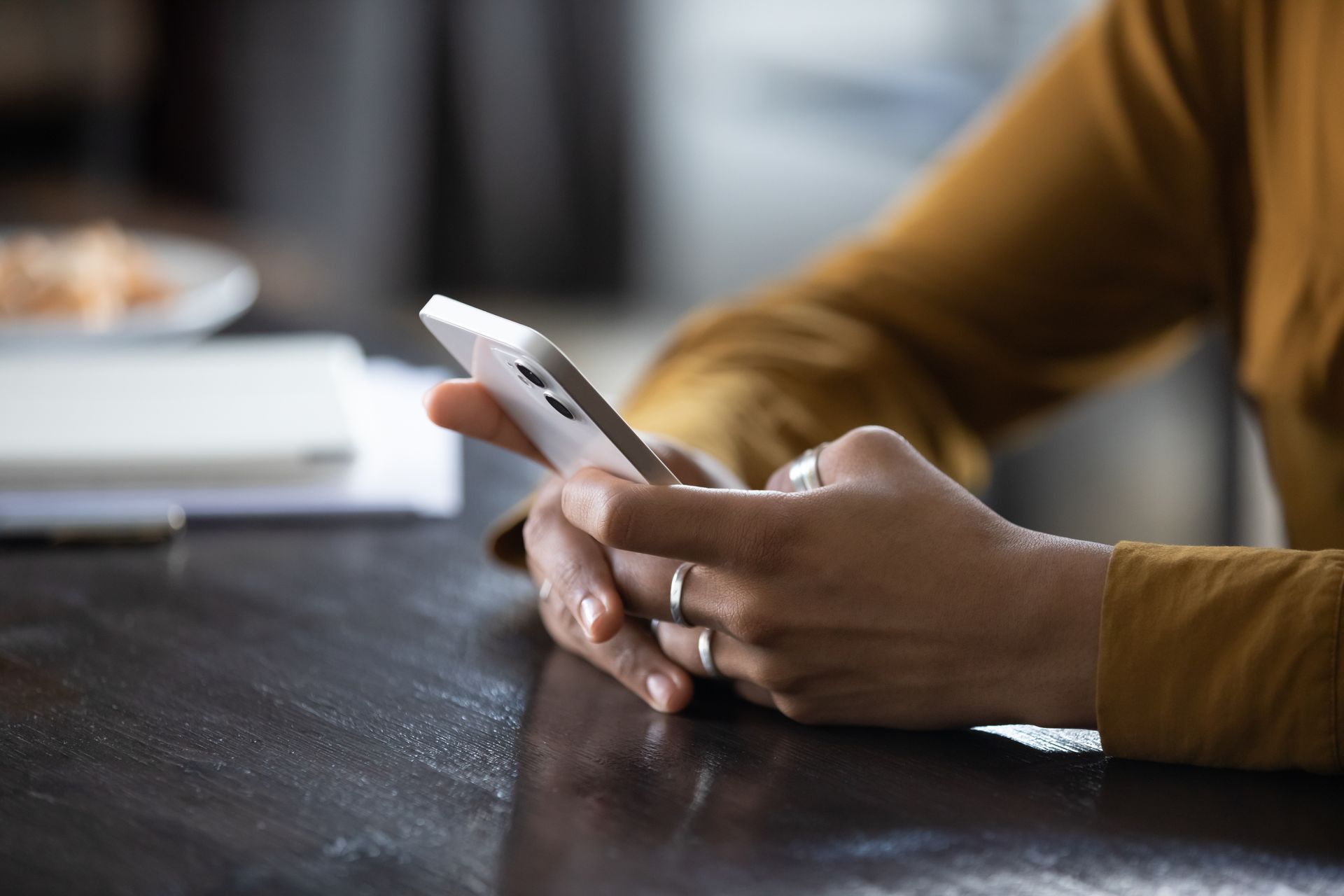 A woman is sitting at a table using a cell phone.