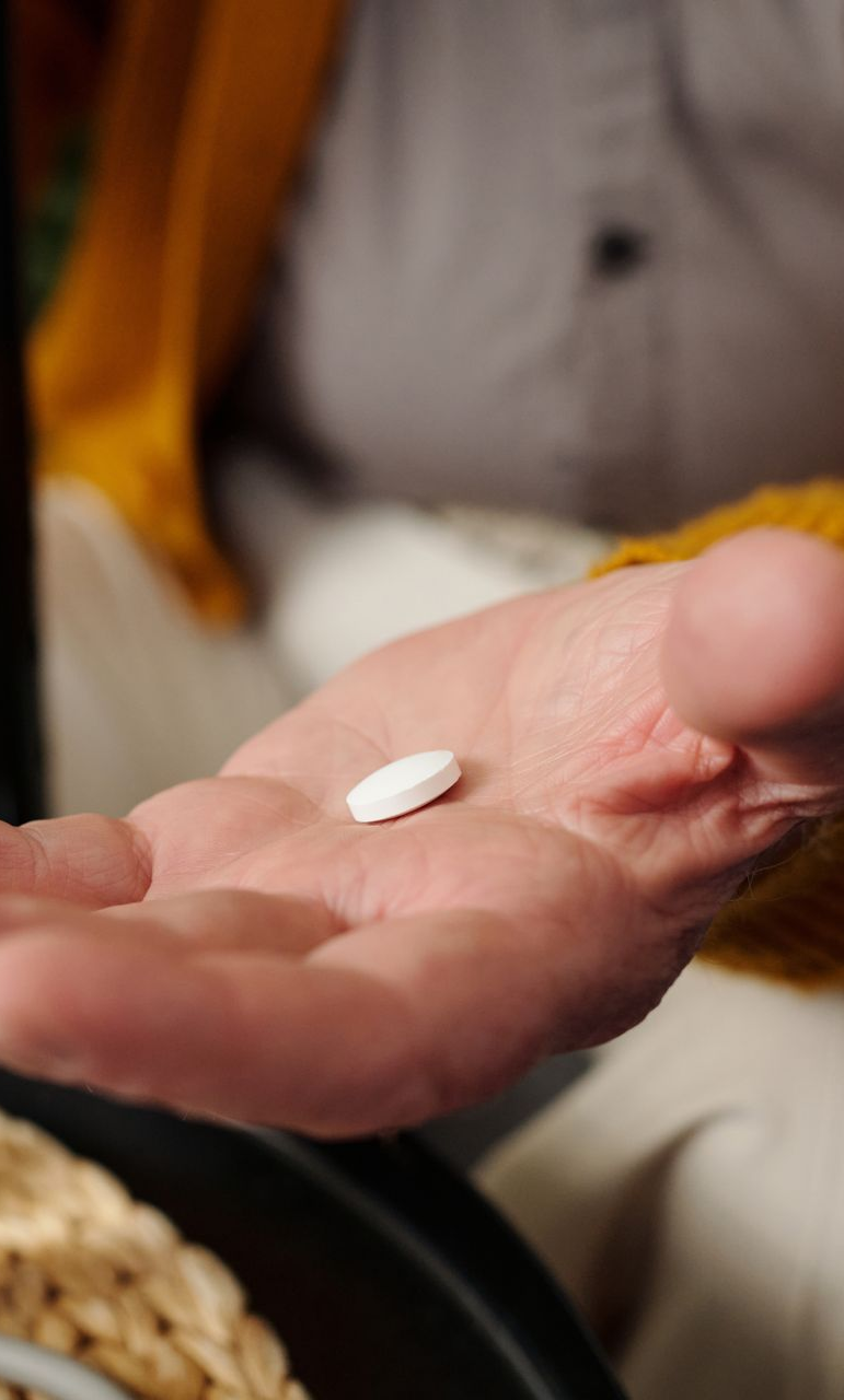 Elderly person holding an medication tablet
