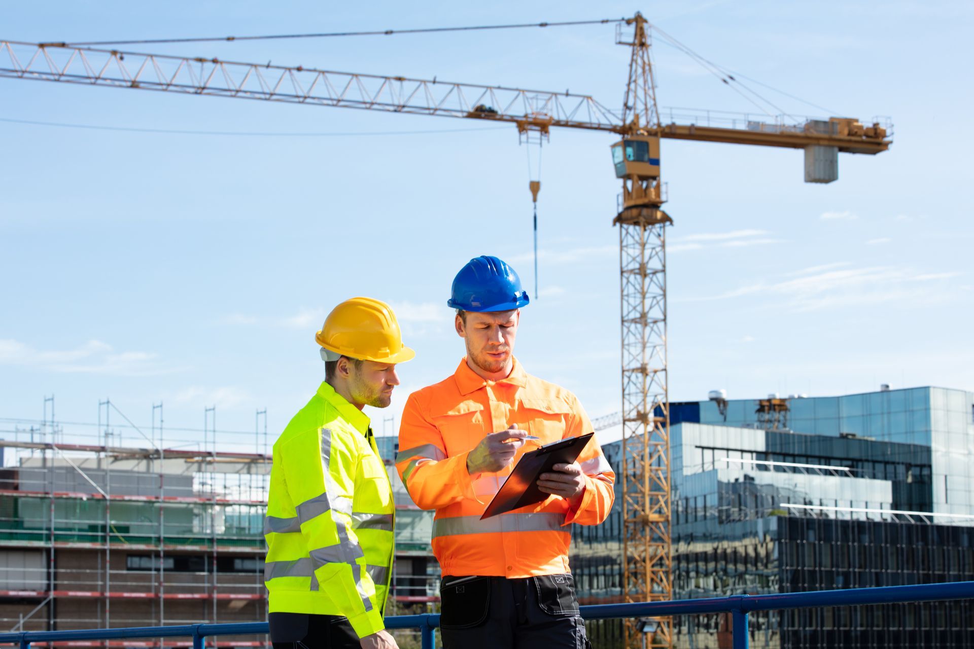 Two Construction Workers Are Looking at a Clipboard at a Construction Site