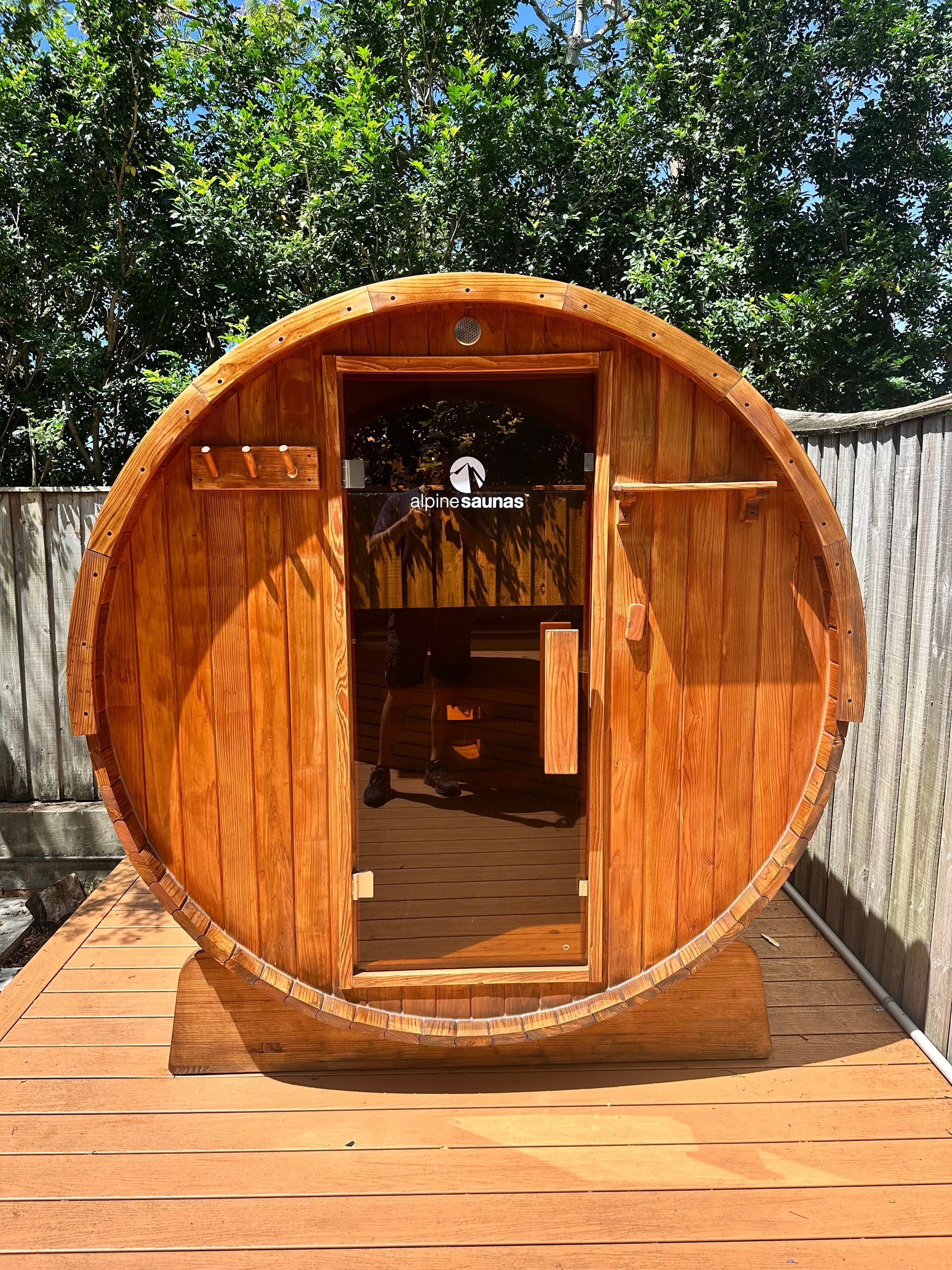 Wooden barrel sauna with glass door outdoors on a wooden deck. completed maintenance 