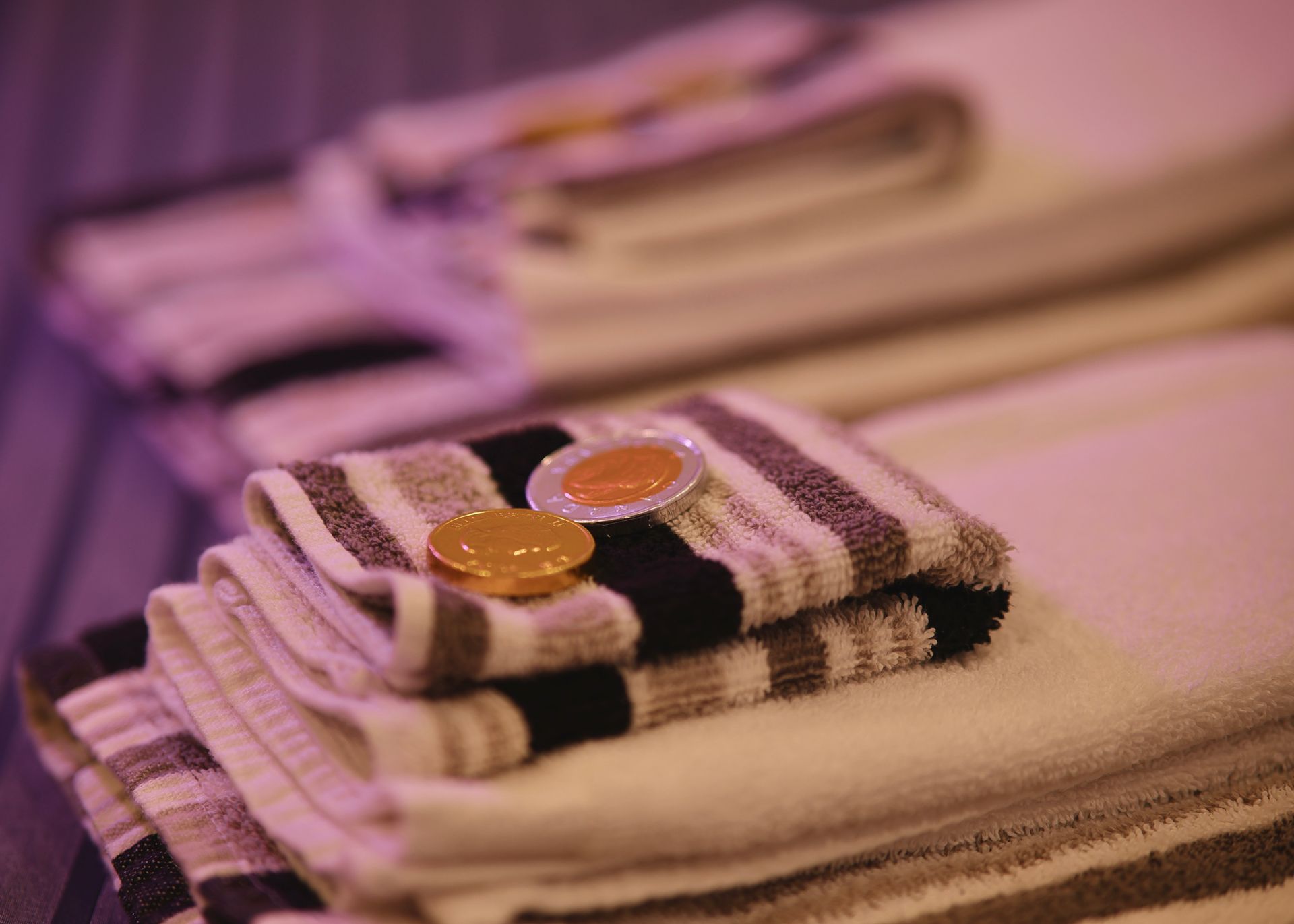 Stacked striped towels with two small golden coins on top.