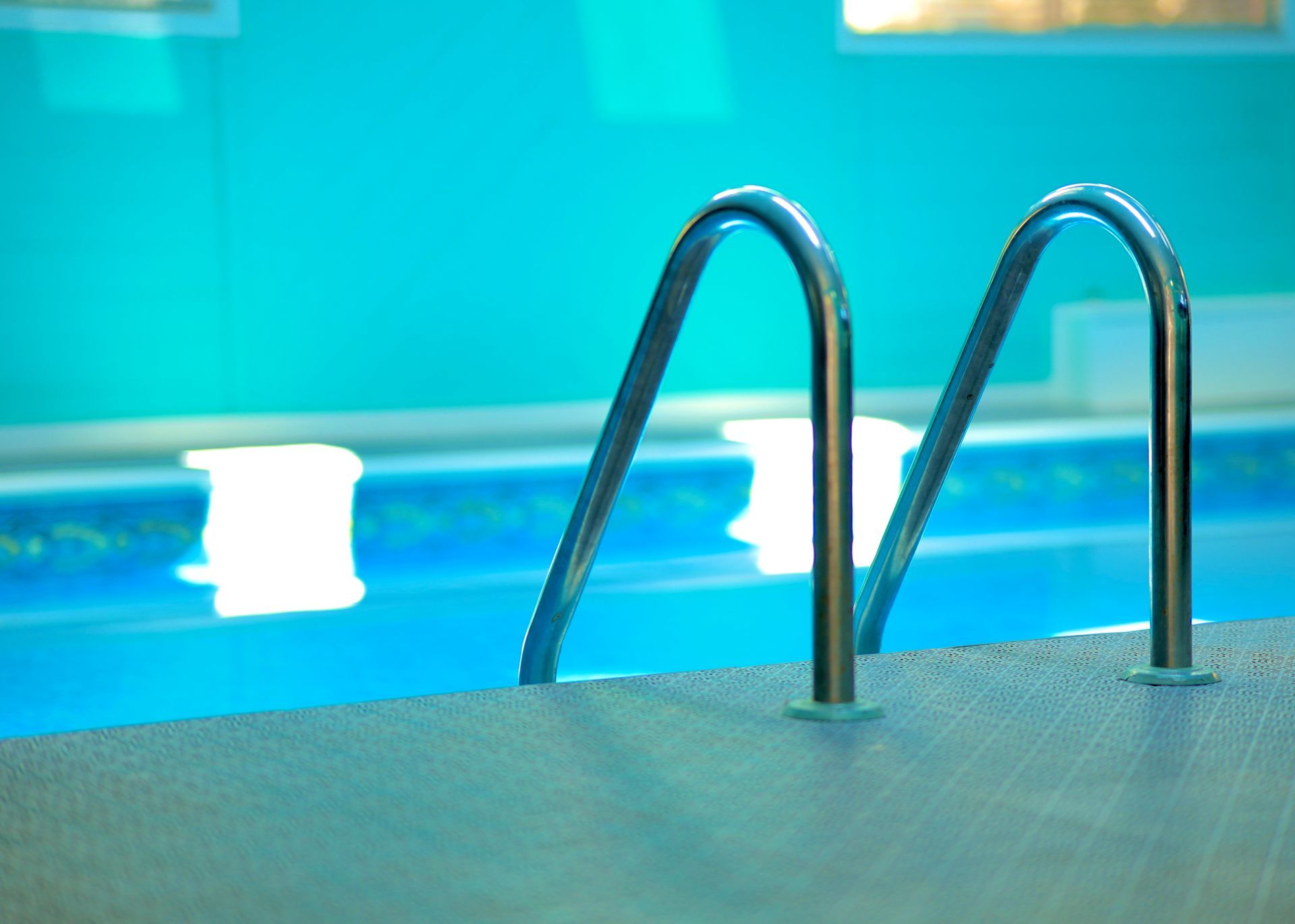 Pool with metal ladder, teal walls, and blue water.