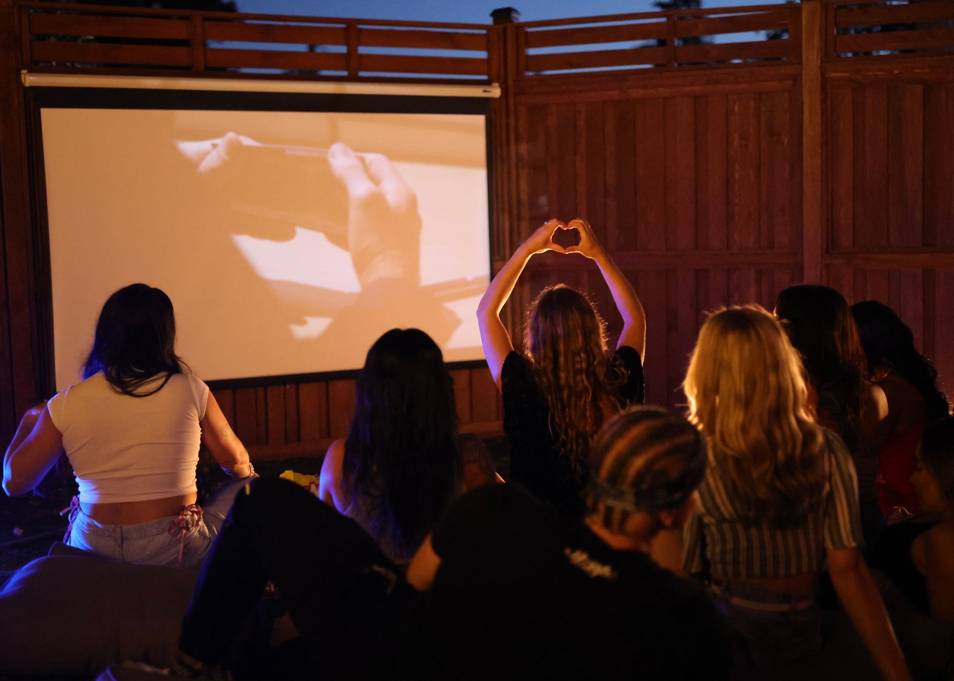 A group of people are sitting in front of a projector screen watching a movie.