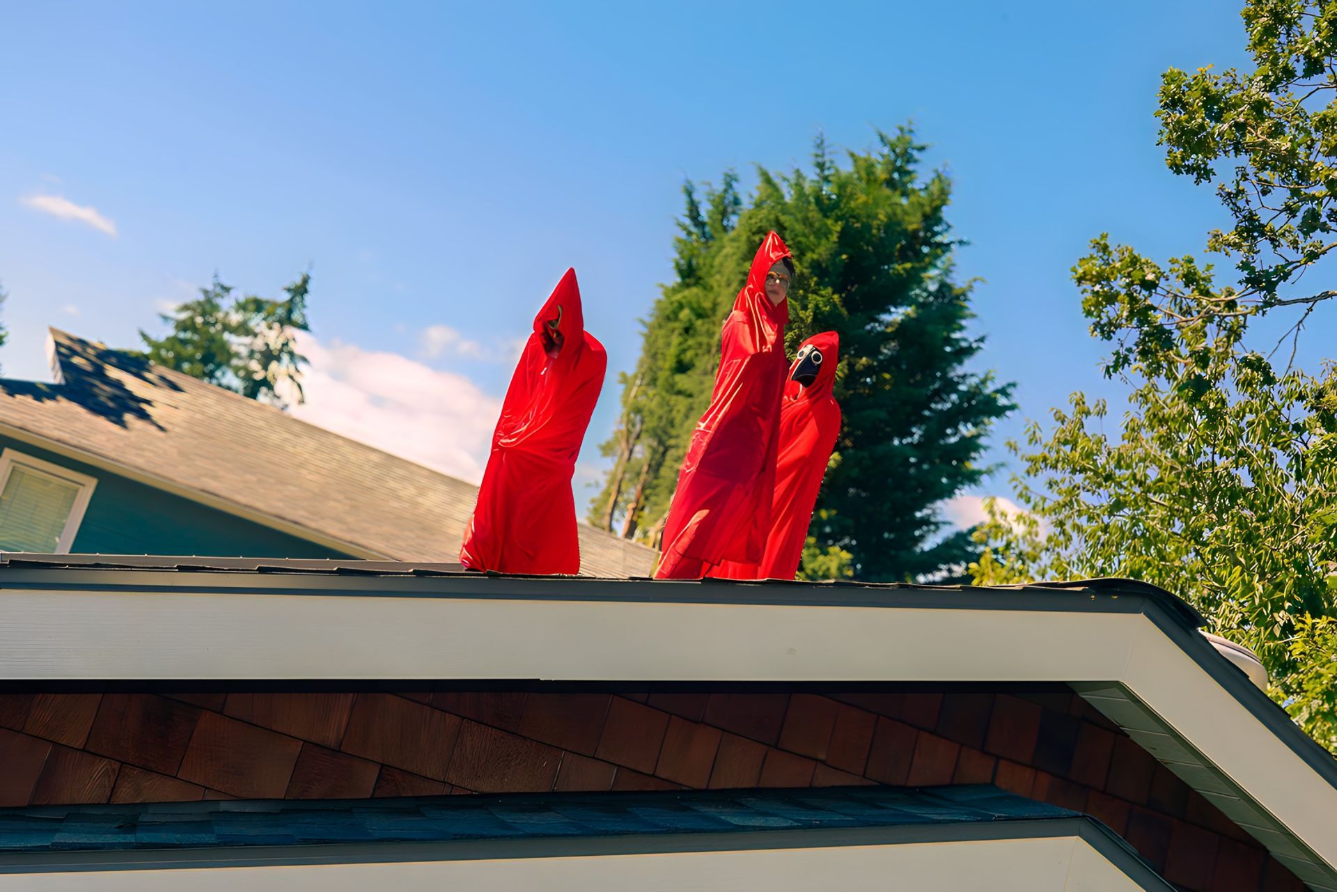 Two red riding hoods are standing on the roof of a house