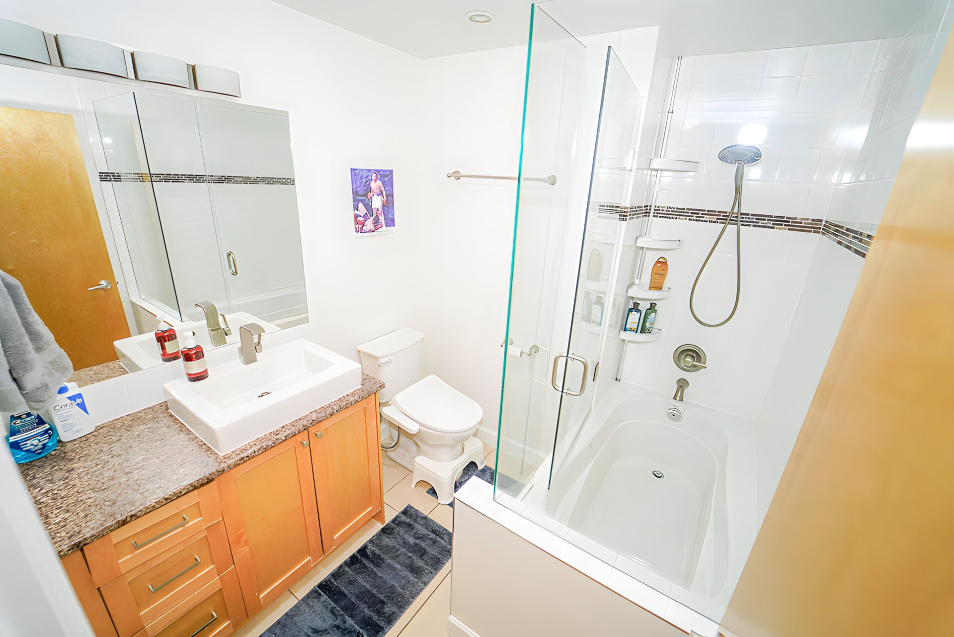 Bathroom with white walls, a shower with glass doors, and a wooden vanity.