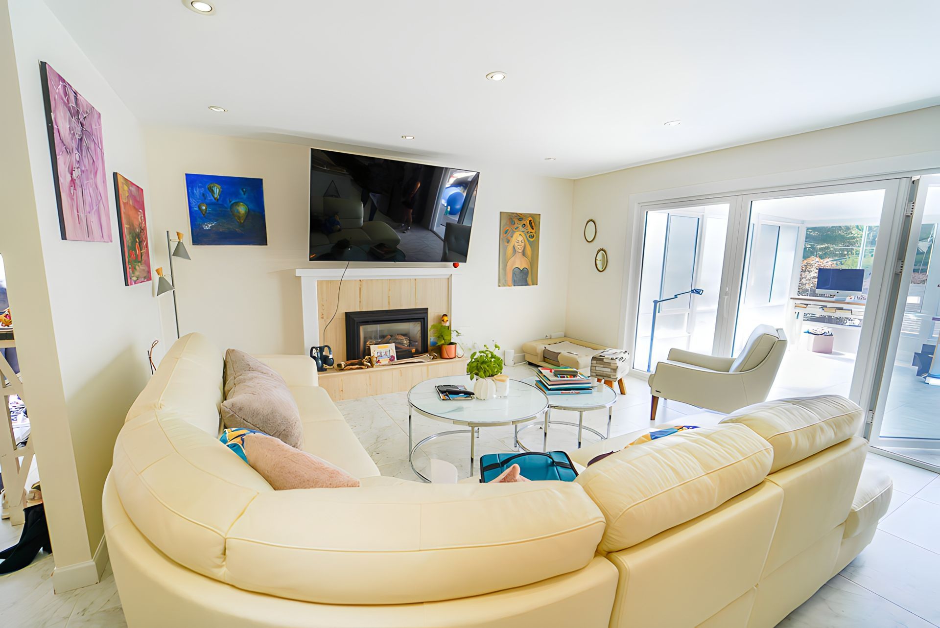 Bright living room with cream sectional, fireplace, TV, glass doors to a patio.