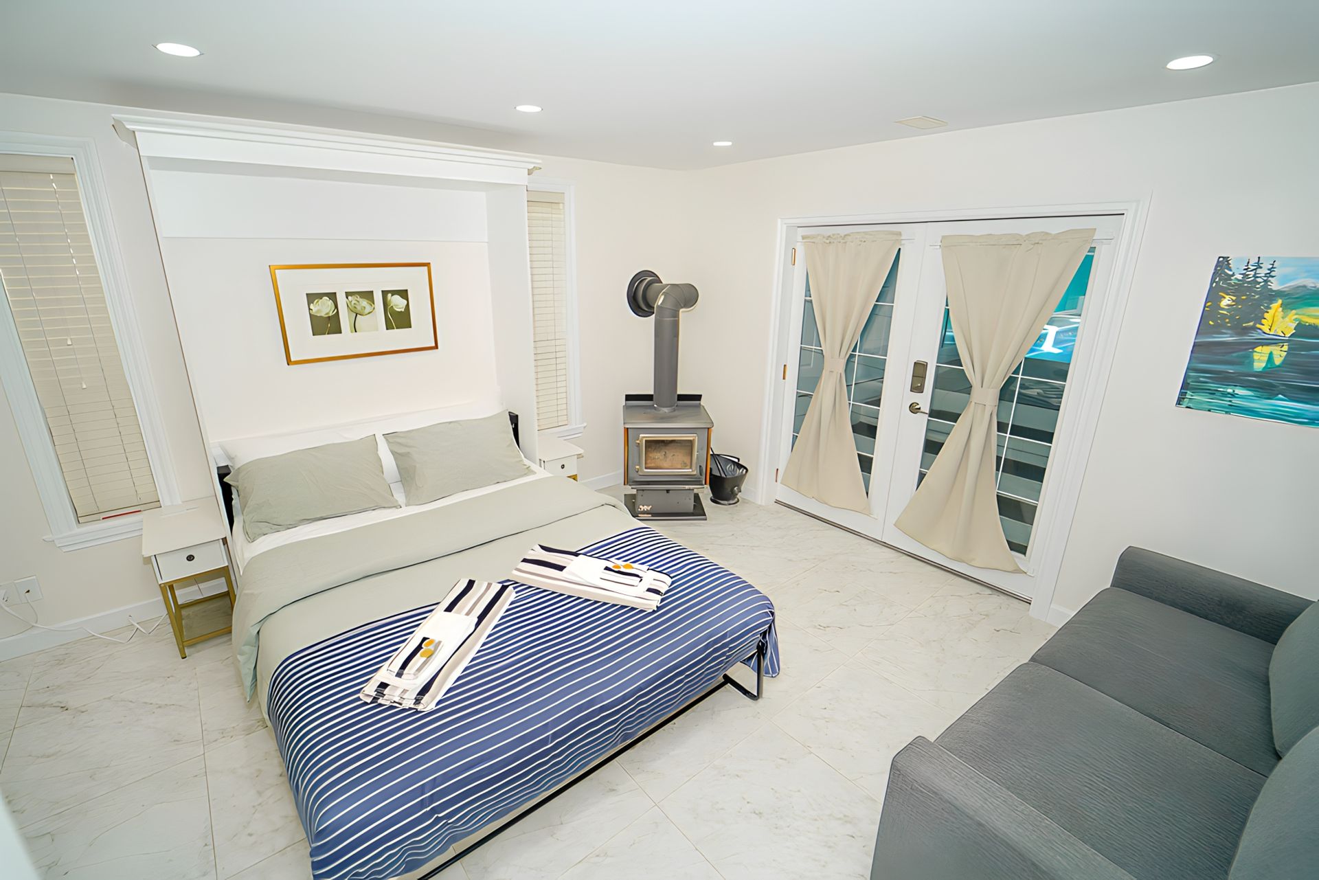 Cozy bedroom with bed, small couch, fireplace, and French doors leading to a patio.
