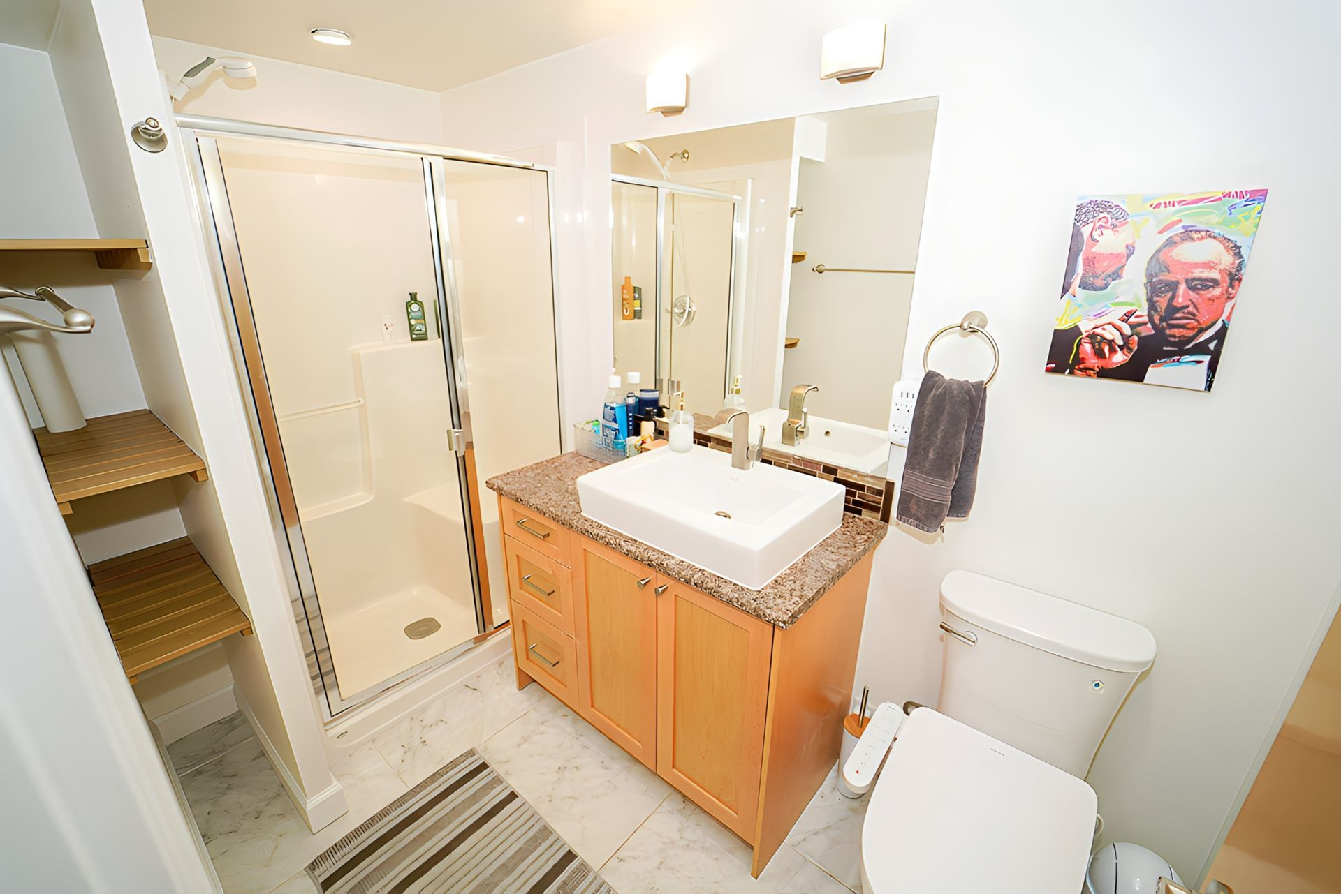 Bathroom with a shower, sink, toilet, and Godfather artwork on the wall.