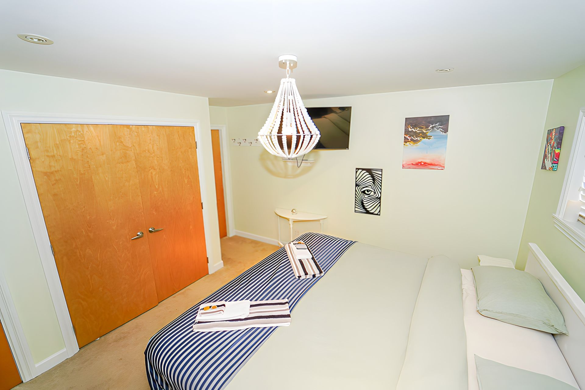 Bedroom with a bed, closet, TV, and decorative light fixture.