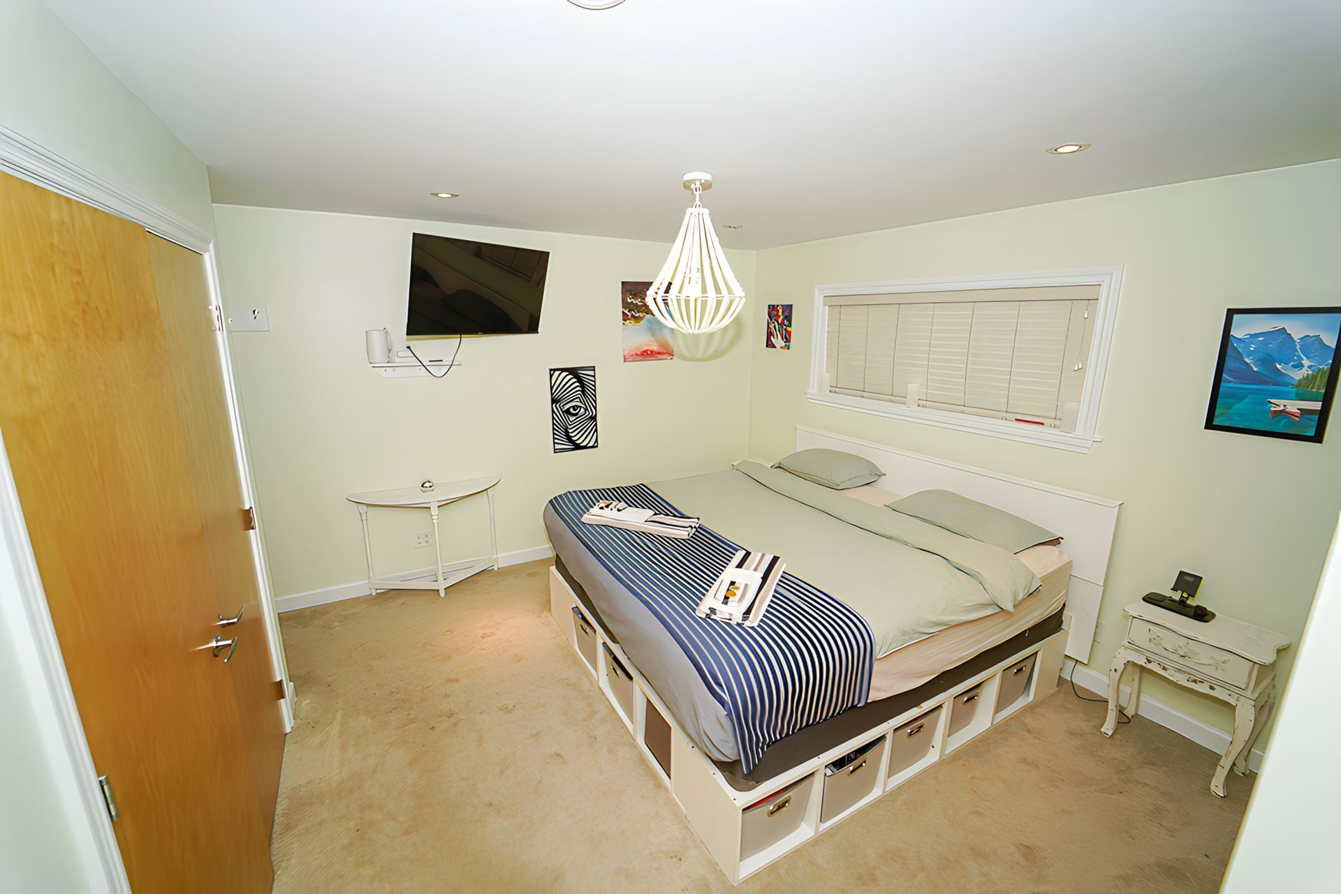Bedroom with a bed, TV, and side tables. Light green walls, beige carpet.