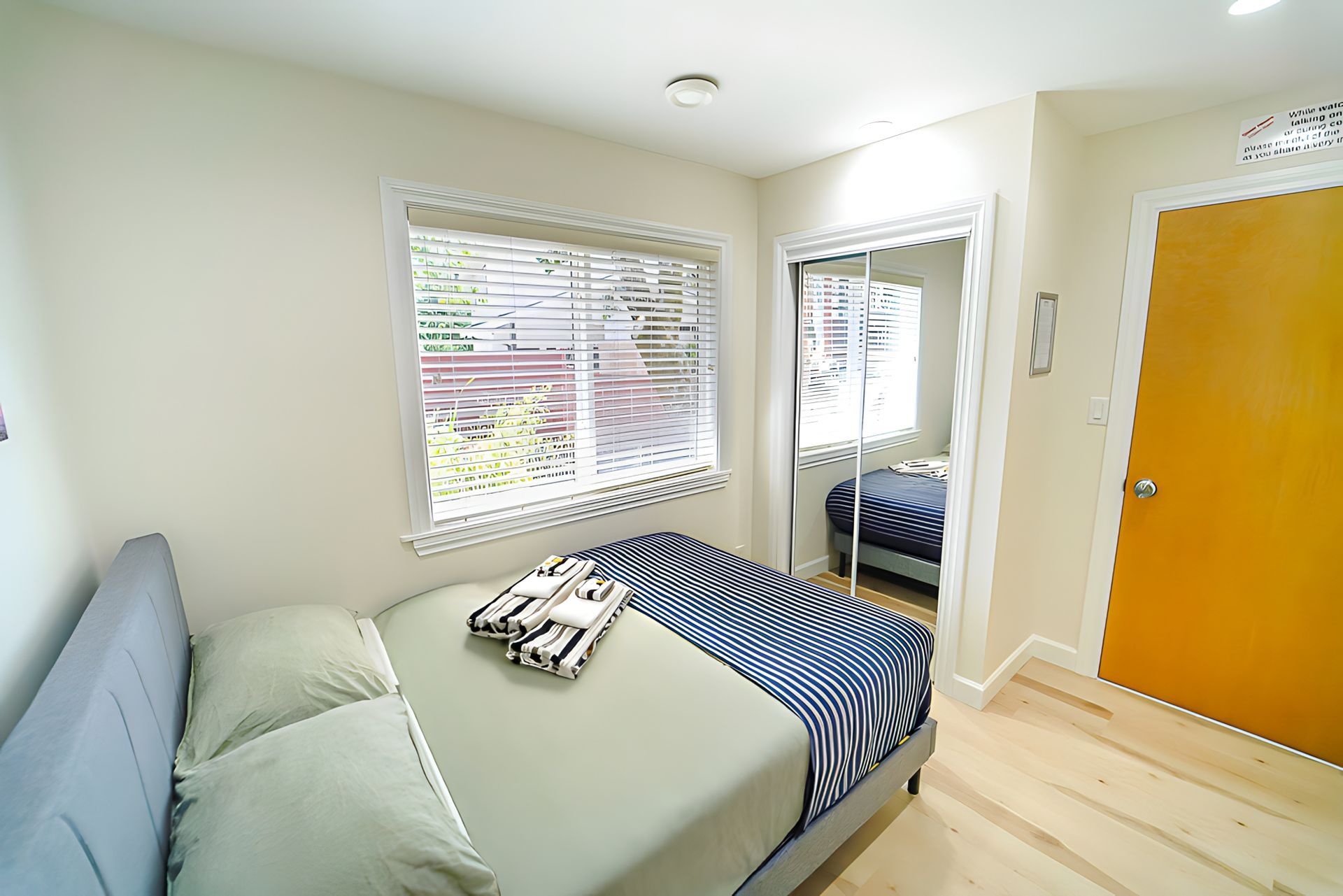 A bedroom with a bed and a window with blinds