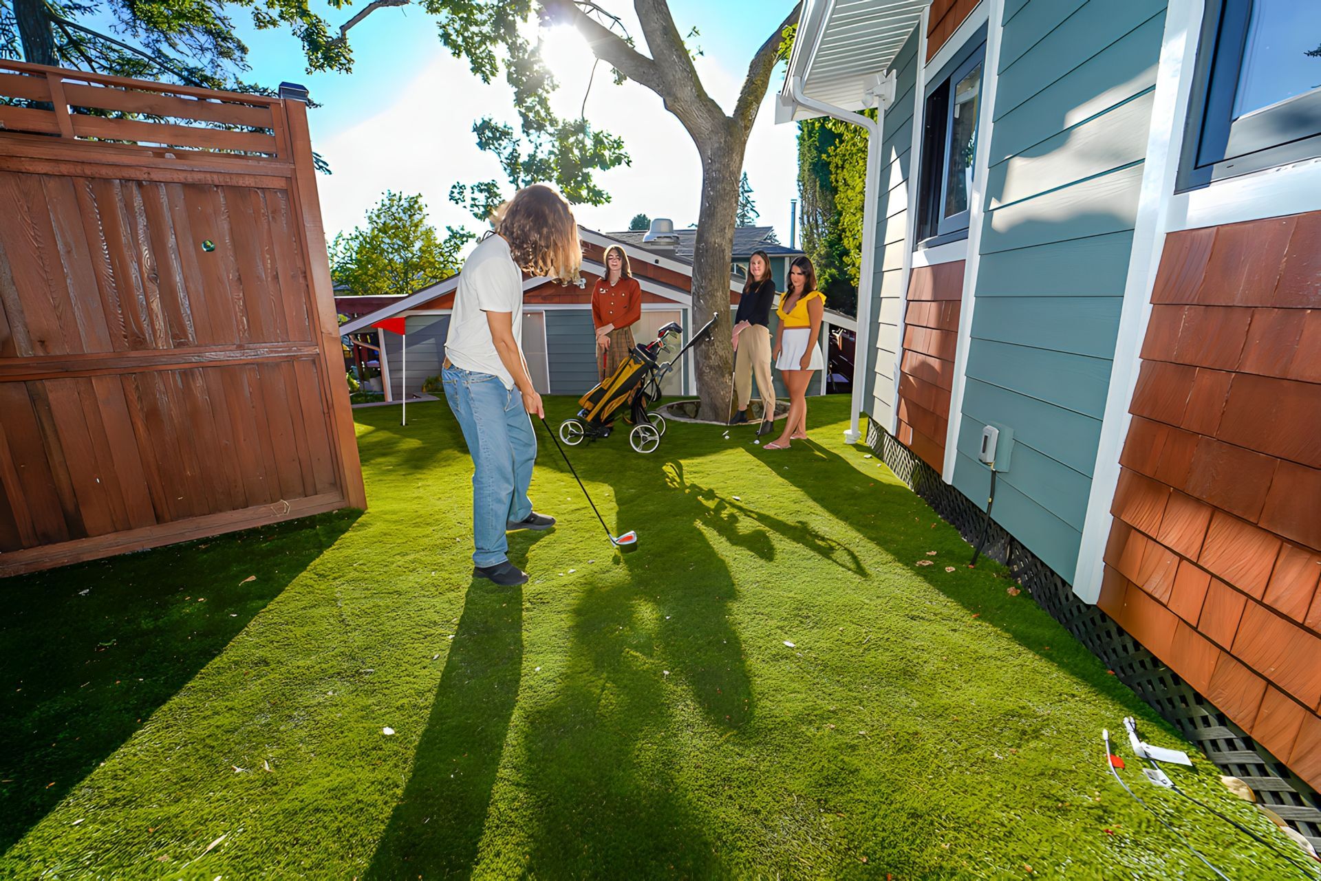 A group of people are playing a game of minigolf in a backyard.