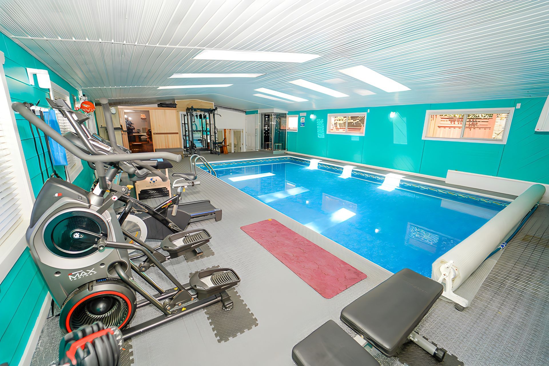An indoor swimming pool surrounded by exercise equipment in a gym.