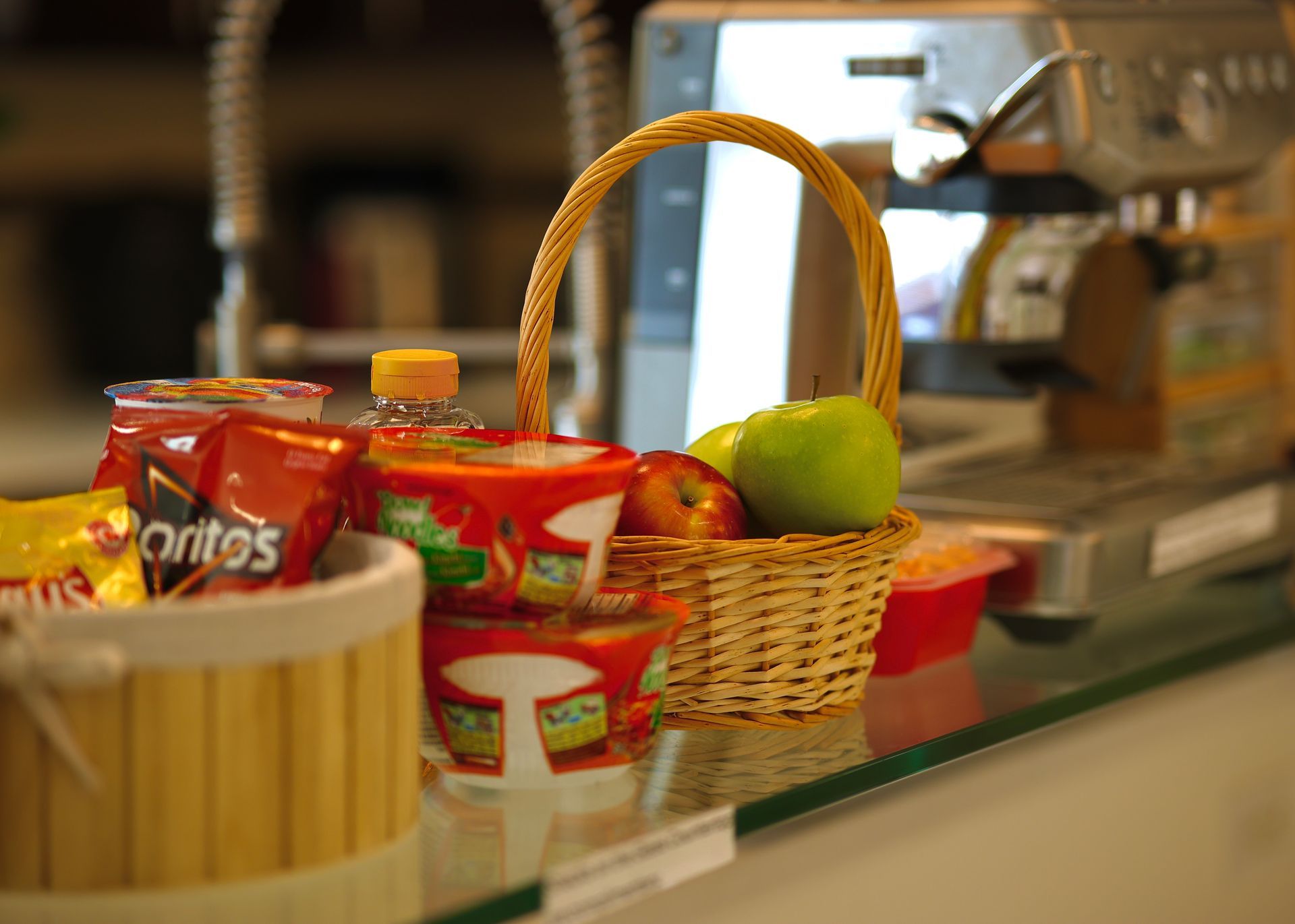 A basket of fruit is sitting on a counter next to a bag of doritos.