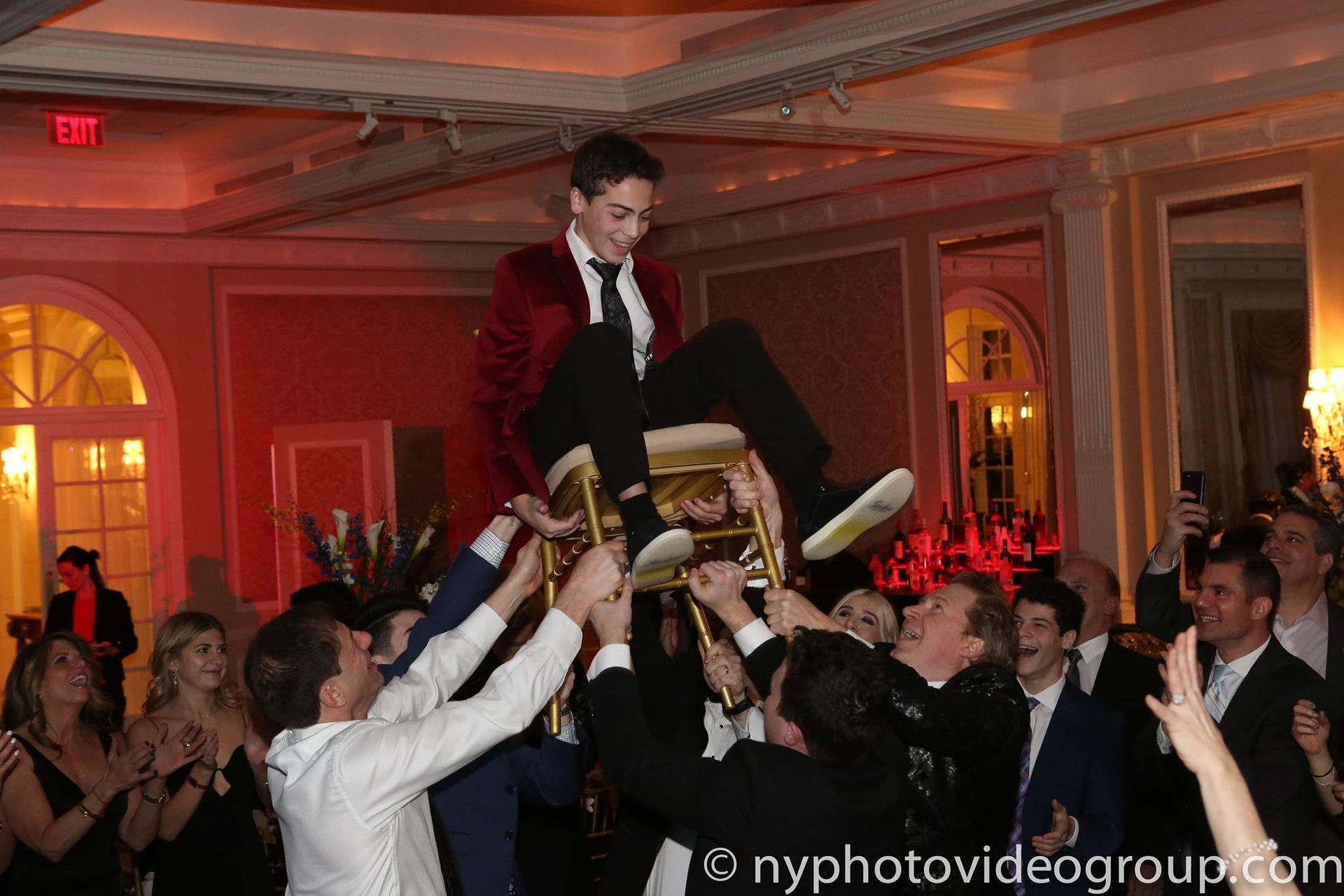 A man in a red suit is being lifted in the air by a group of people.
