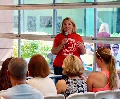 Agency founder Cynthia Macluskie is speaking into a microphone in front of a group of people.