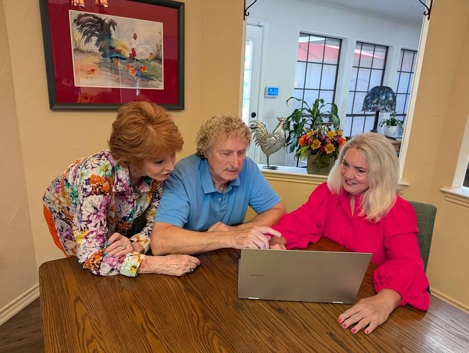Agency founder Cynthia Macluskie is sitting at a table looking at a laptop with Medicare clients.