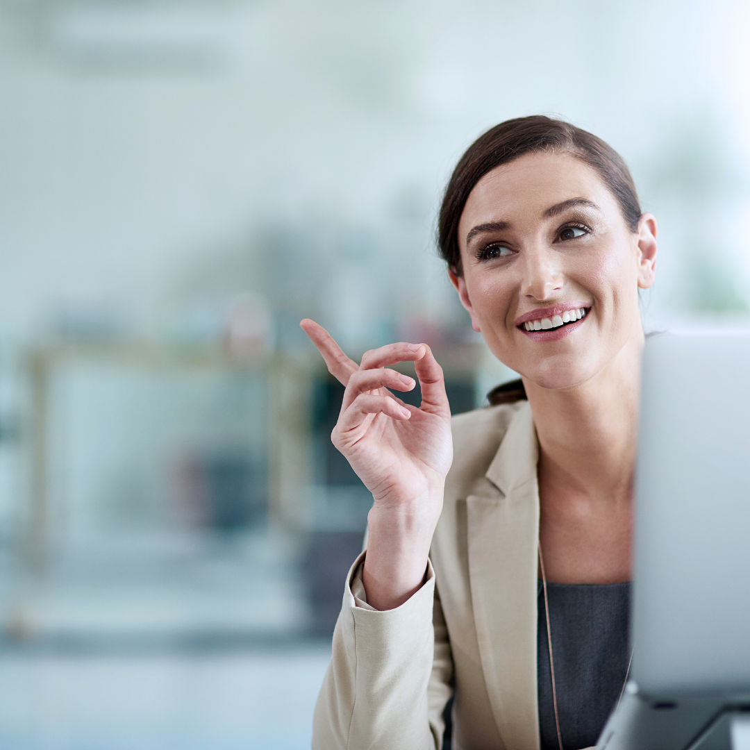 A woman is sitting in front of a laptop computer and smiling.