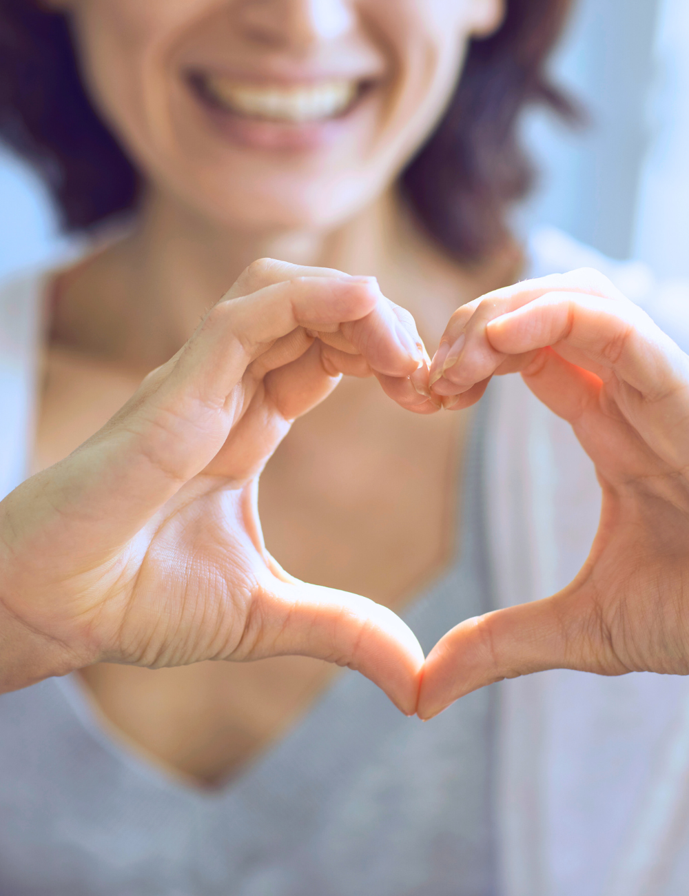 A woman is making a heart shape with her hands.