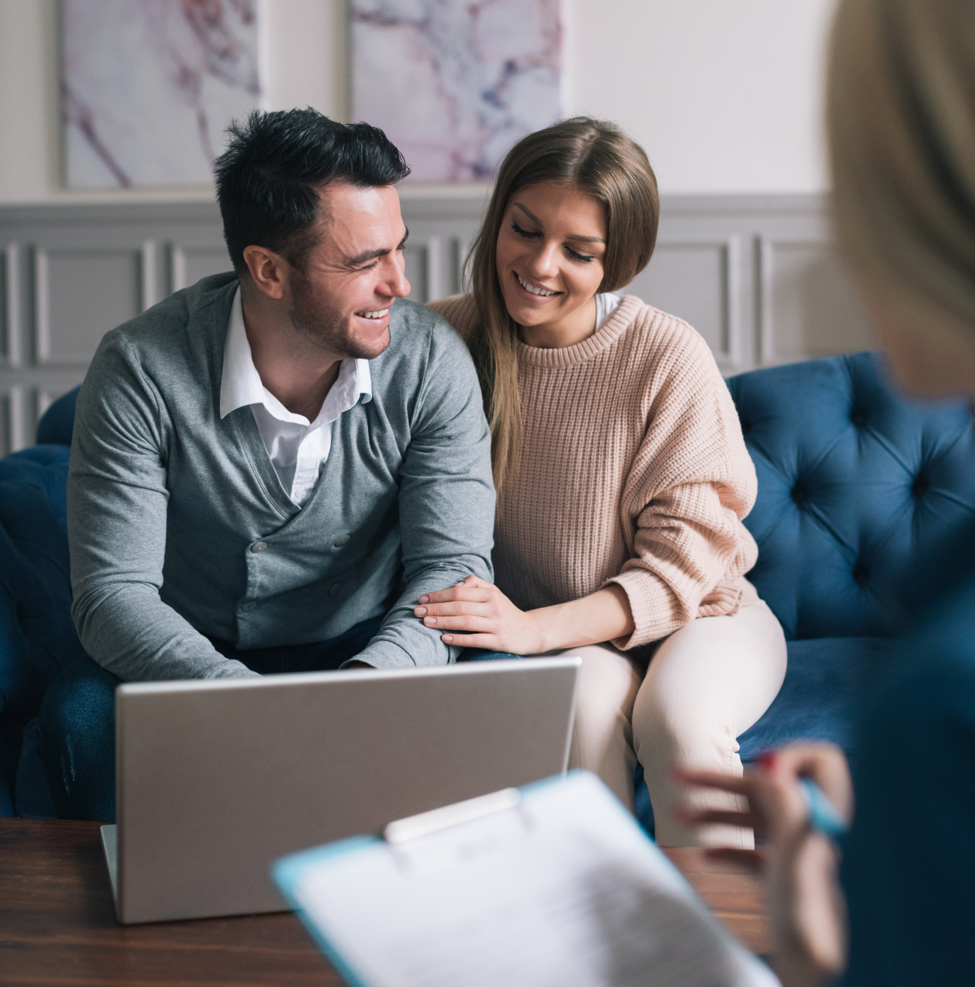 A man and woman are sitting on a couch looking at a laptop.