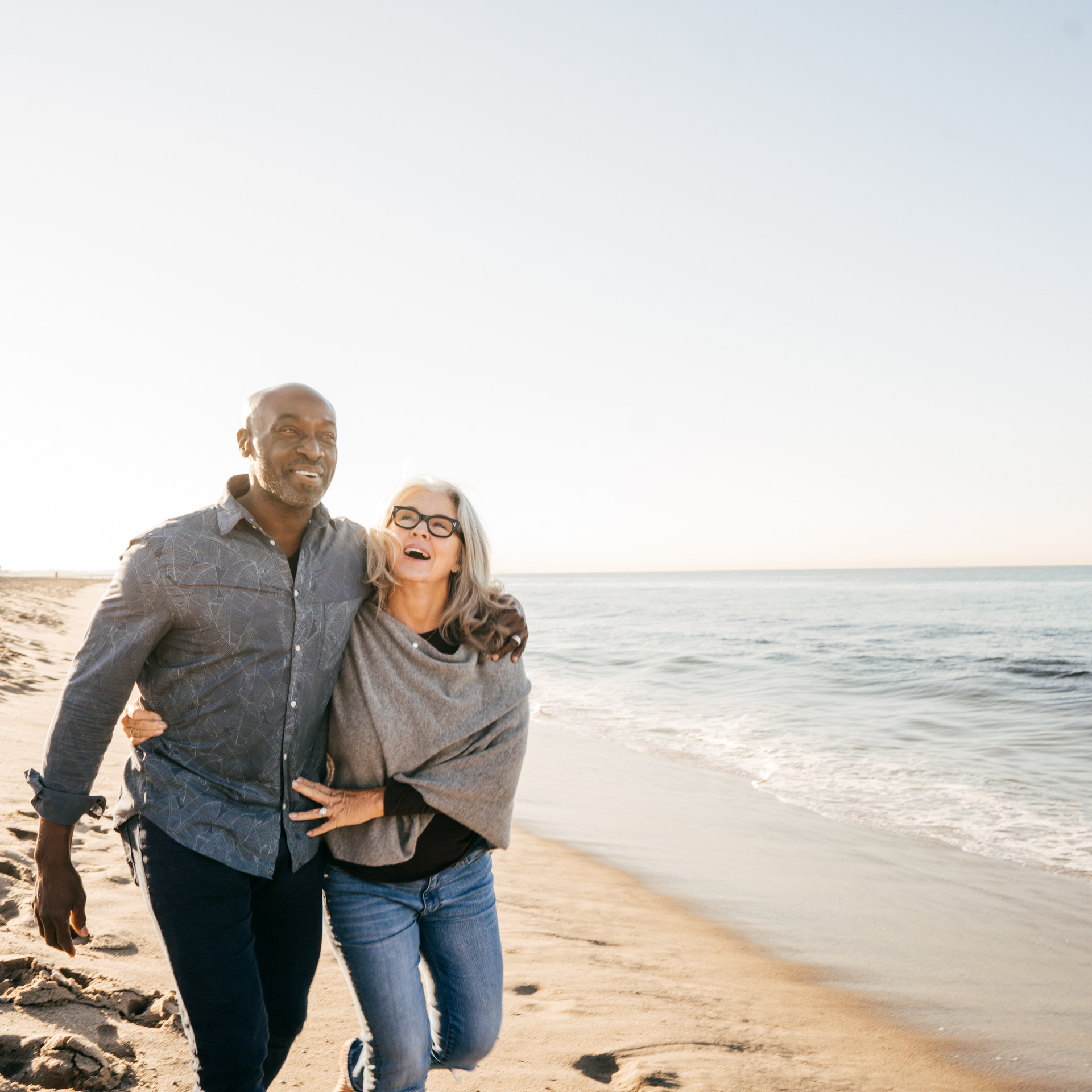 A man and a woman are walking on the beach.