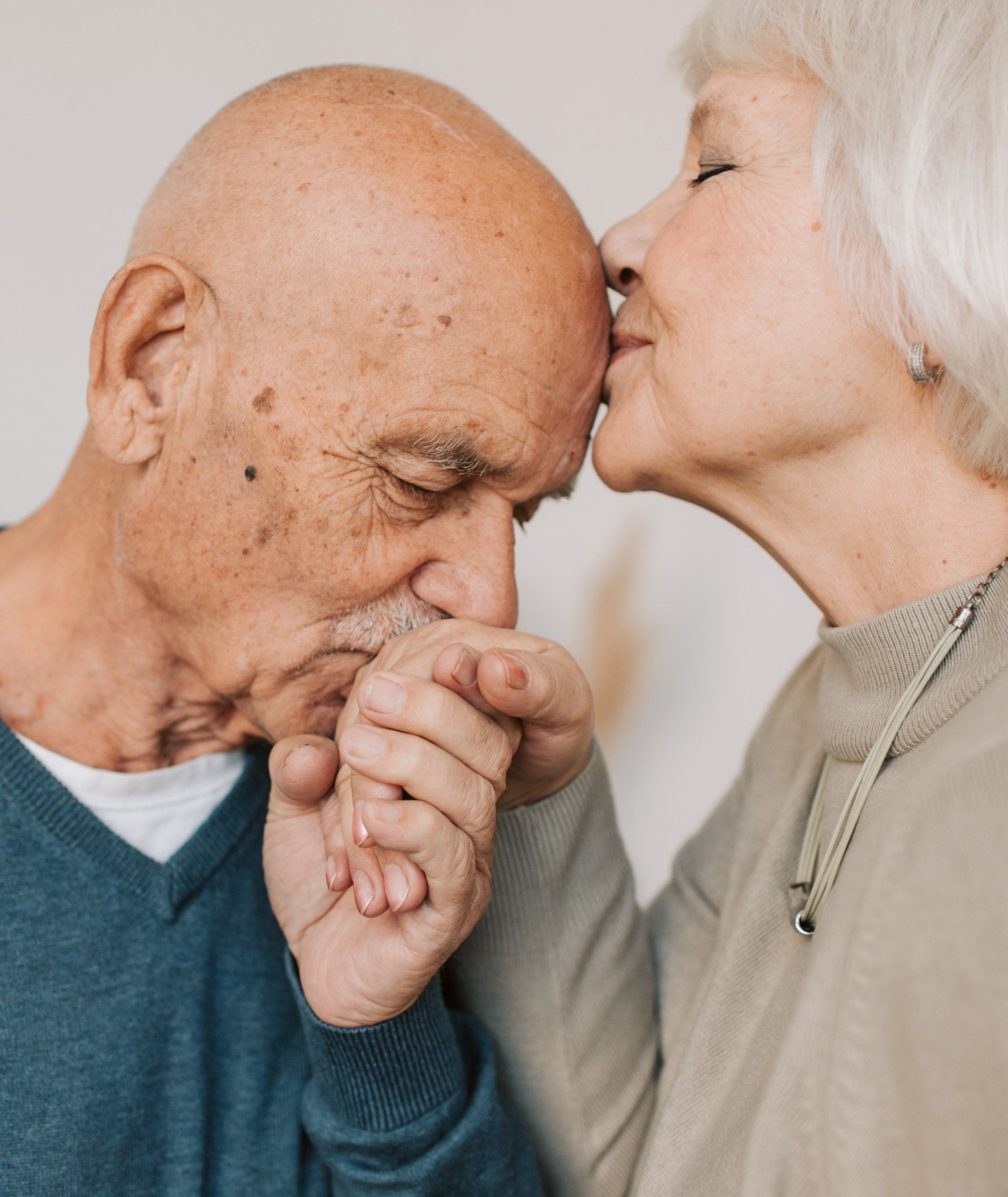 A woman is kissing a bald man on the forehead.