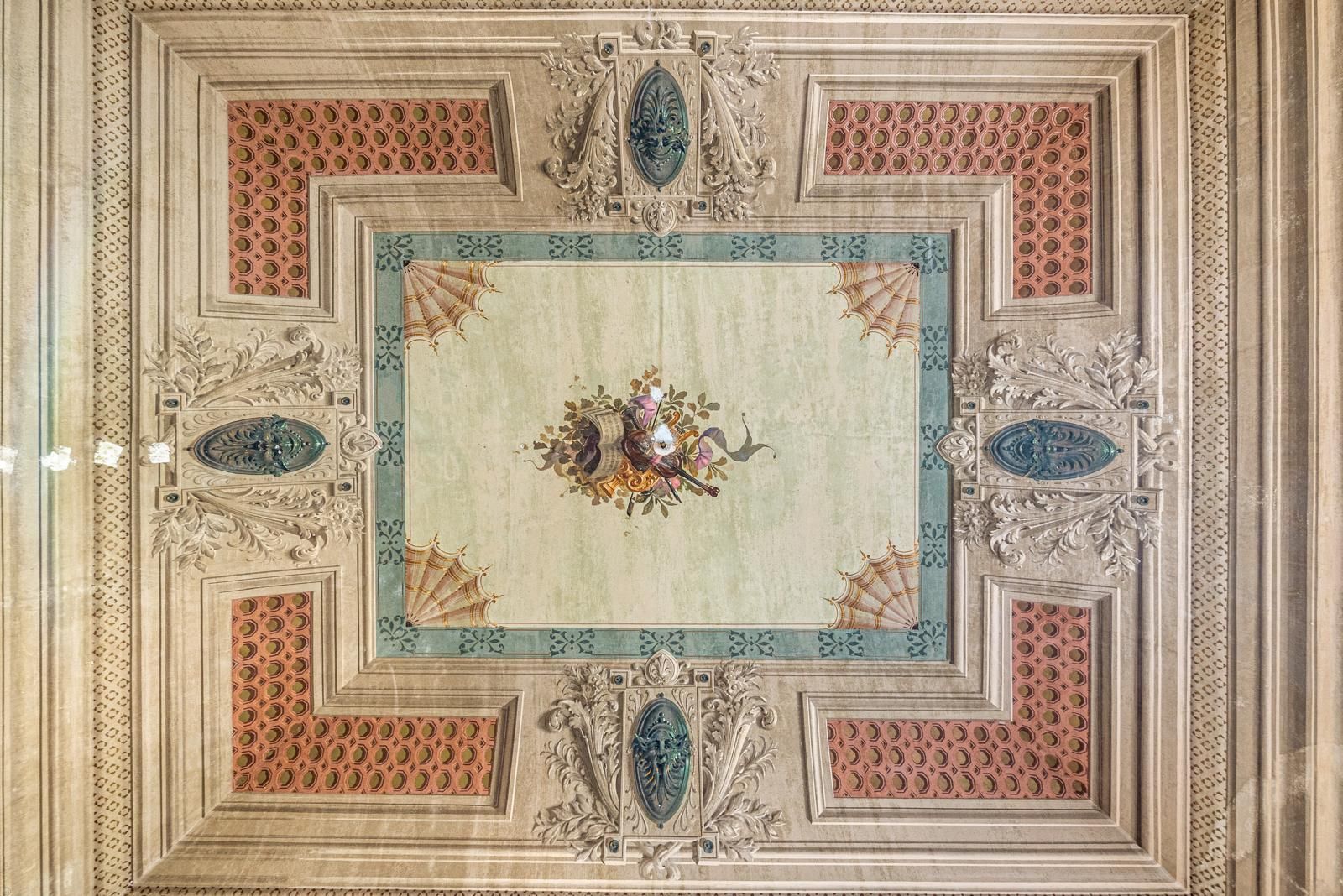 Soffitto decorato e dettagliato con pannelli decorativi beige, pesca e verde acqua e centro floreale.