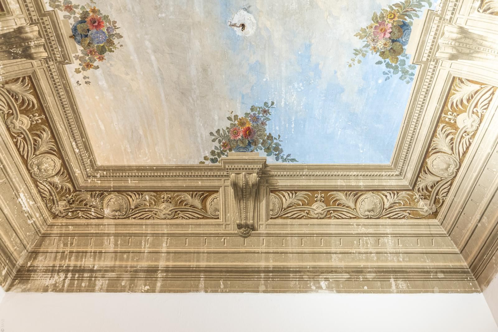 Soffitto decorato con cielo dipinto e dettagli floreali, in una stanza.