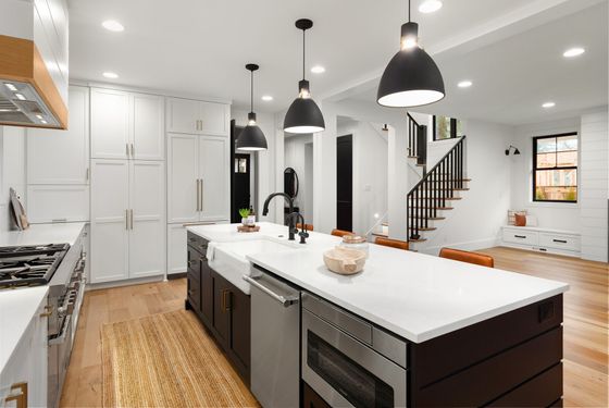 A kitchen with stainless steel appliances and a large island in the middle.