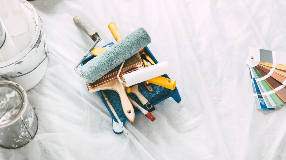 A bunch of paint rollers and brushes on a table.