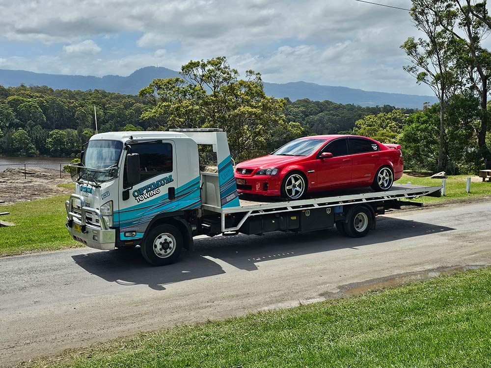 A Red Car Is Sitting On Top Of A Tow Truck — Optimum Towing in Bomaderry, NSW