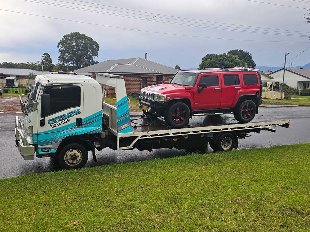 A Red Hummer Is Being Towed By A Tow Truck — Optimum Towing in Bomaderry, NSW