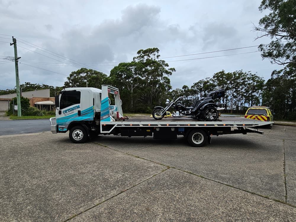 A Tow Truck is Carrying a Motorcycle on the Back of It — Optimum Towing in Sanctuary Point, NSW