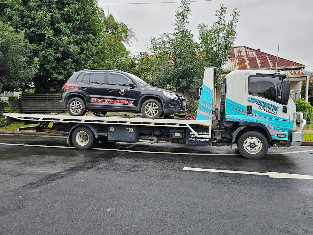 A Black Suv is Being Towed by a Tow Truck — Optimum Towing in Kiama, NSW
