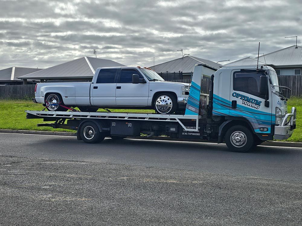 A White Truck Is Being Towed By A Tow Truck — Optimum Towing in Nowra, NSW