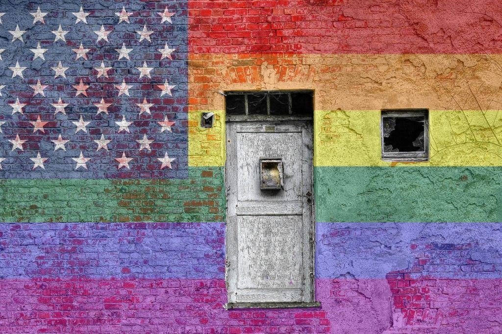 A brick wall with a rainbow flag painted on it and a door.
