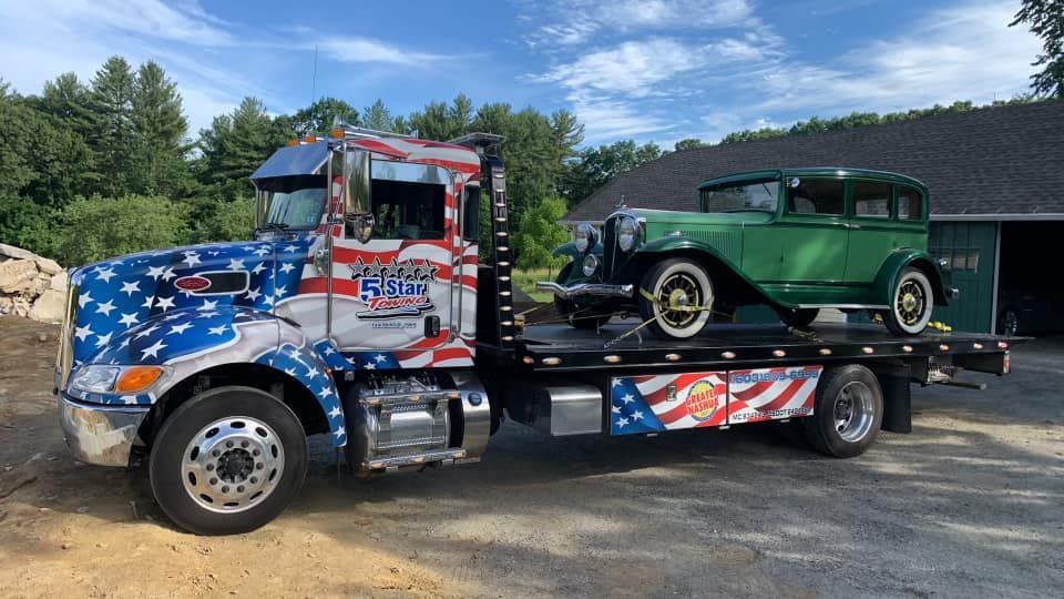 A tow truck with two old cars on the back of it.