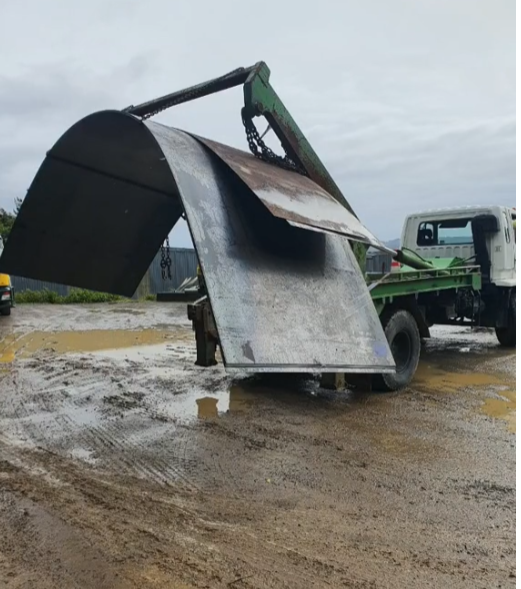 A dump truck is carrying a large piece of metal.