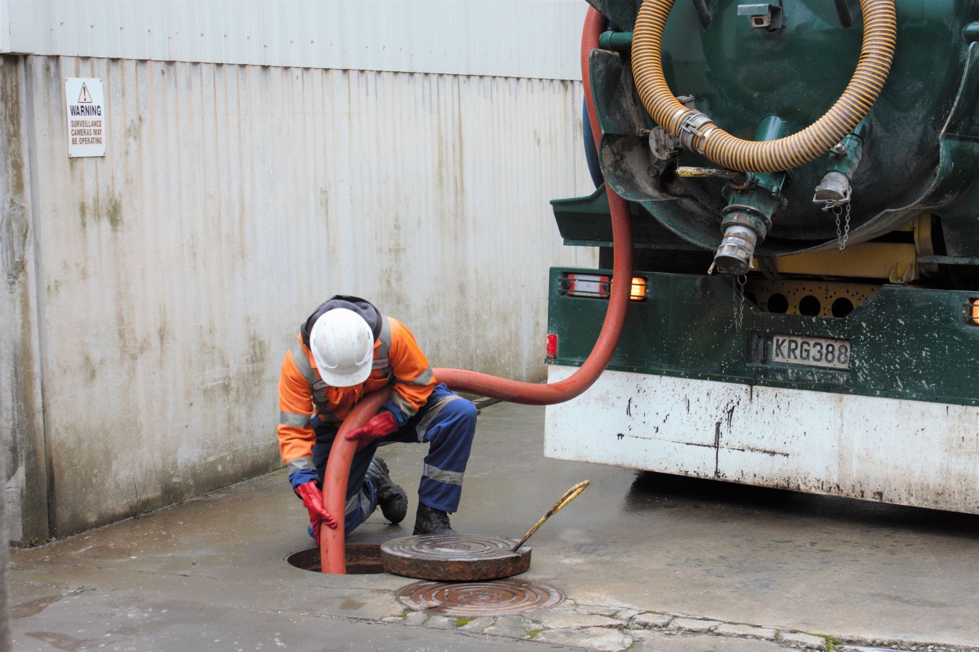A man is working on a manhole cover next to a truck.