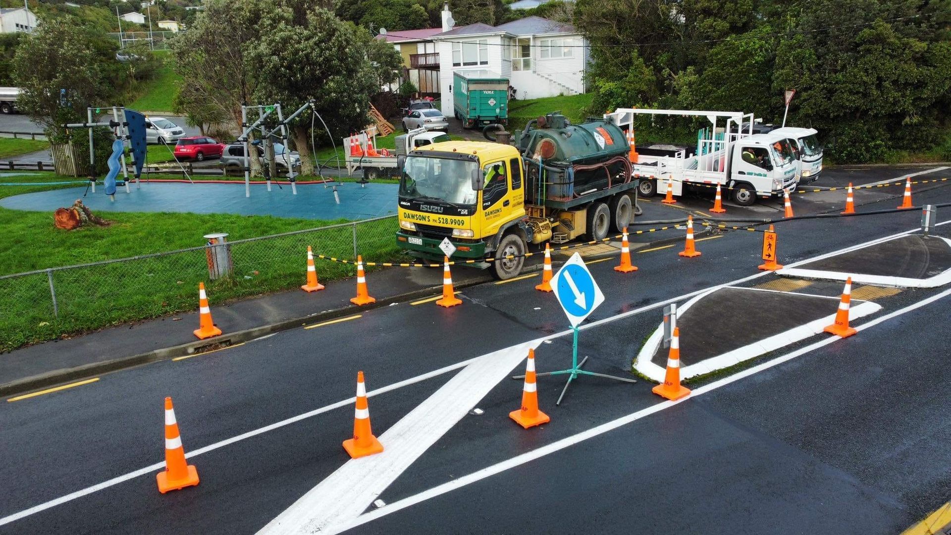 A yellow truck is driving down a road surrounded by orange cones.