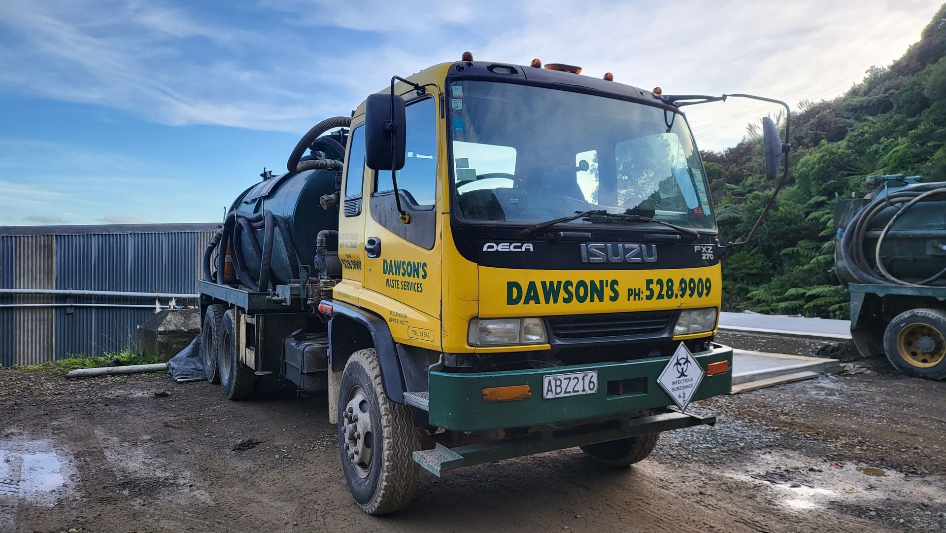 A yellow and green truck is parked in a muddy field.