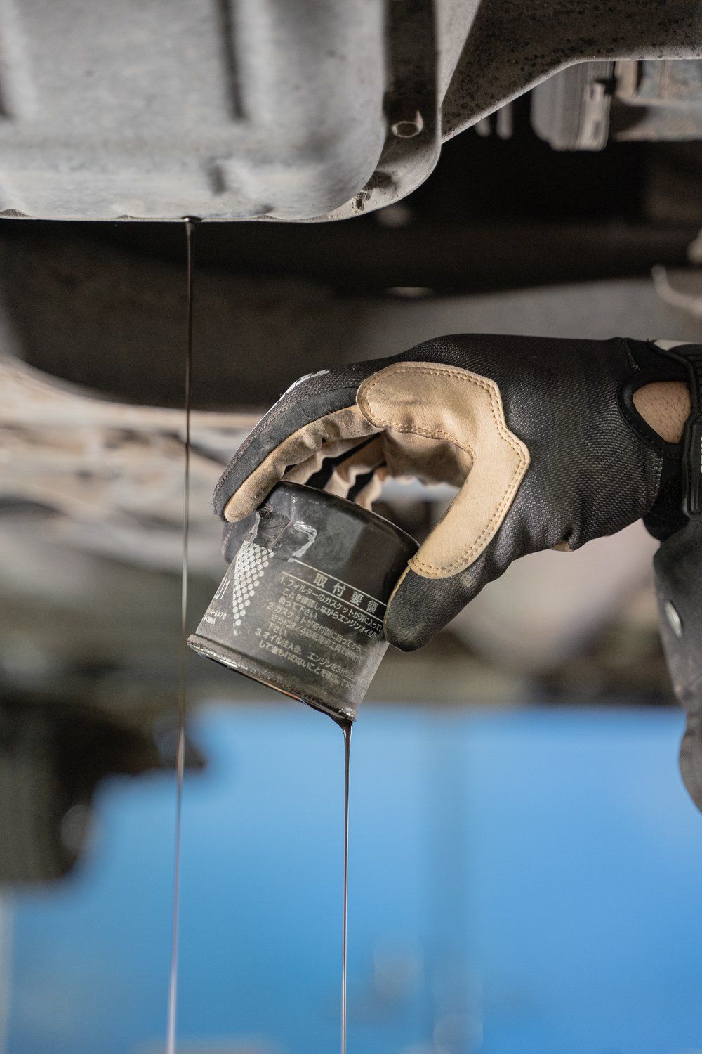 A person is holding a oil filter under a car.