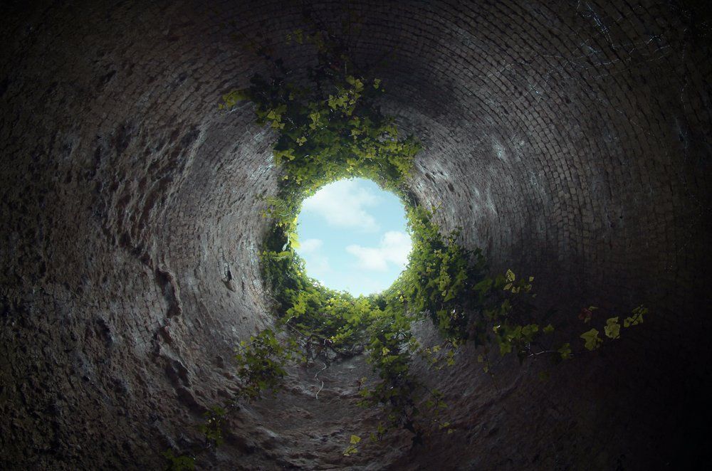 Looking up at the sky through a hole in a tunnel.