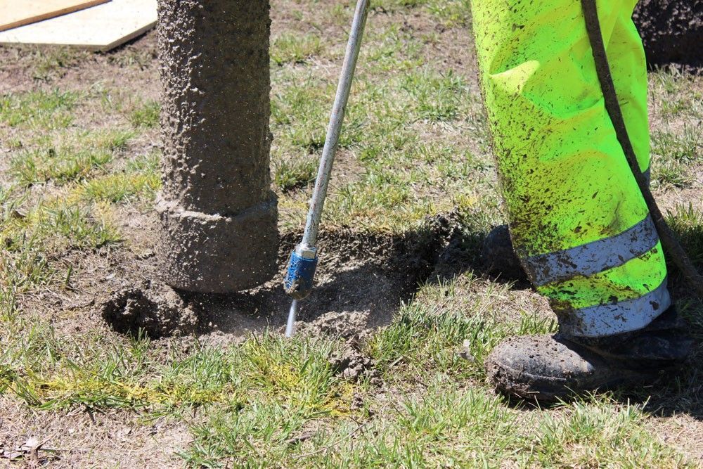 A person in yellow pants is digging a hole in the grass.