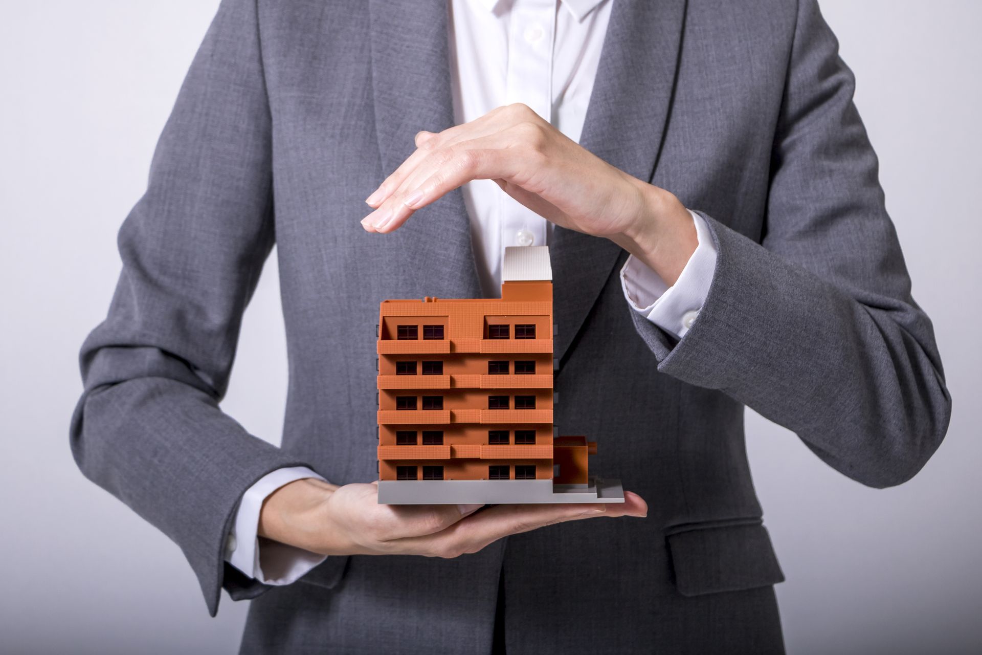 a man in a suit is holding a model of a building